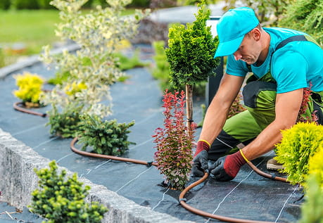 A landscaper with employer-sponsored coverage in Idaho is installing irrigation lines in a garden.