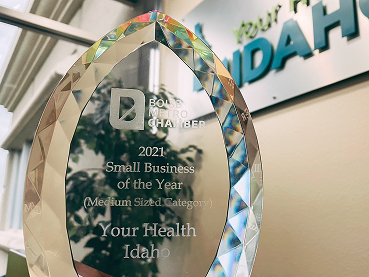 A teardrop-shaped glass award trophy engraved with "Boise Metro Chamber 2021 Small Business of the Year (Medium Sized Category) - Your Health Idaho," displayed in front of a wall with the Your Health Idaho logo.