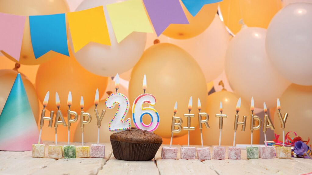 A muffin and other treats with candles for a 26th birthday.